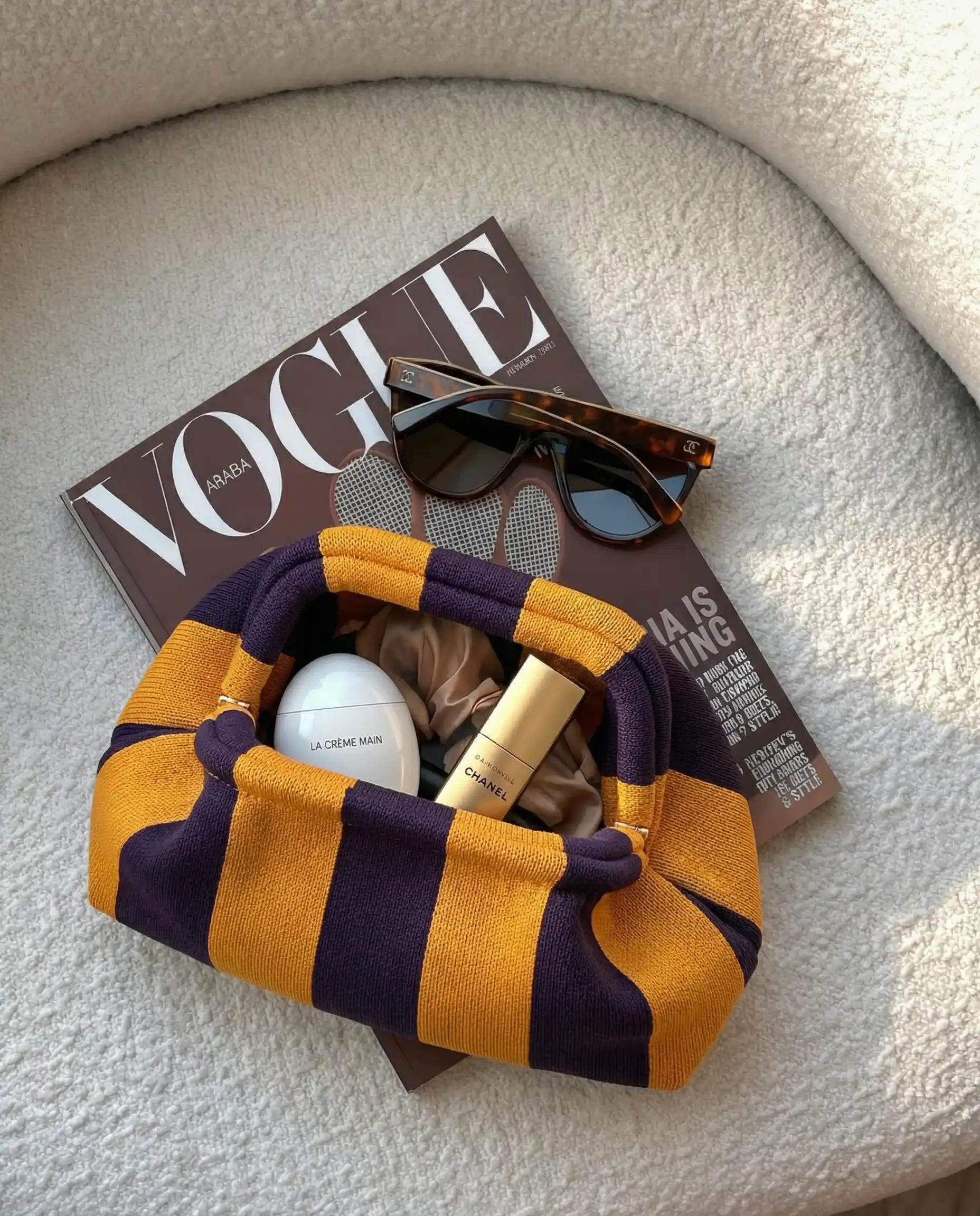 Striped fabric pouch with cosmetic items on a Vogue magazine